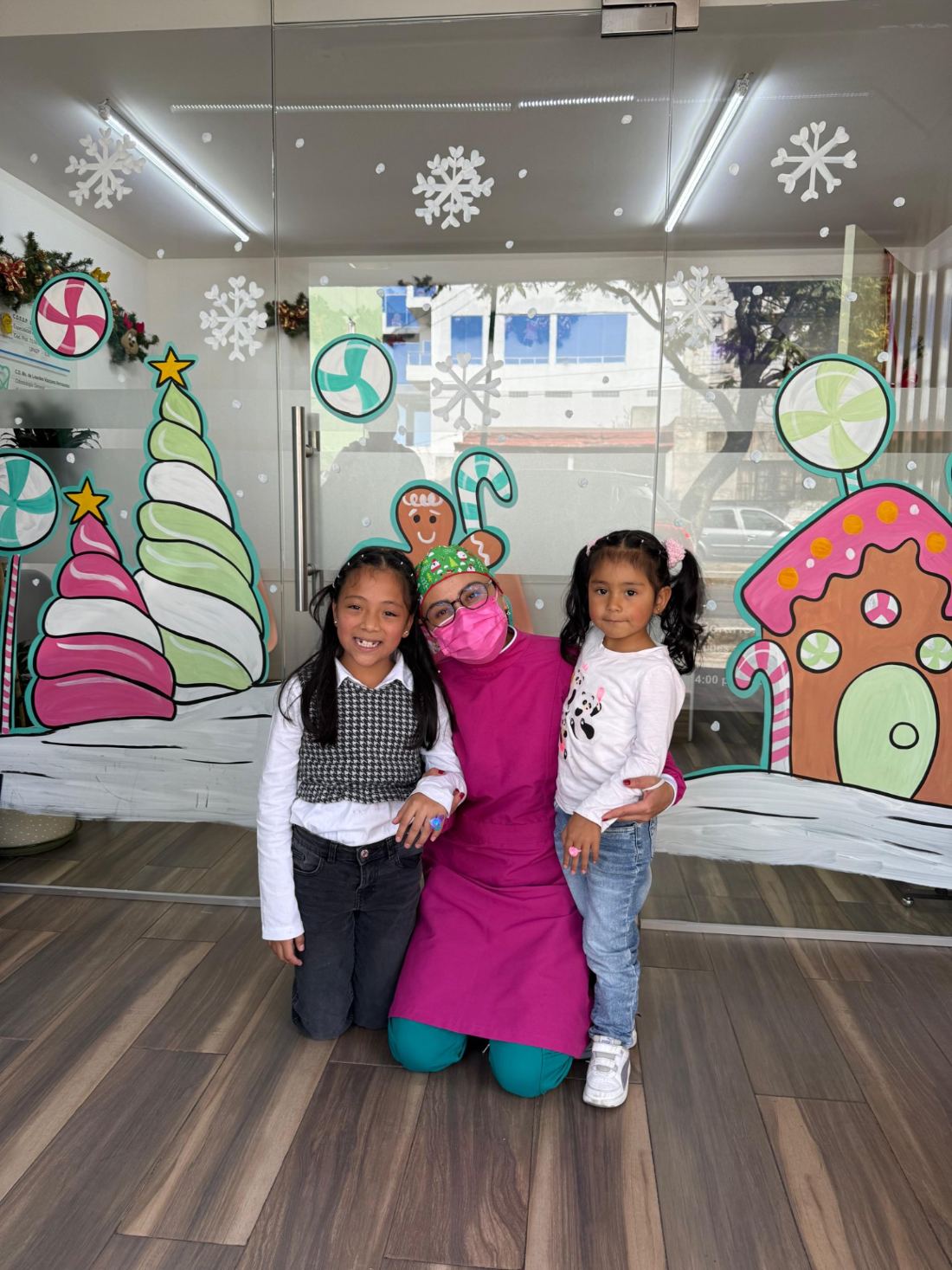Entrada del consultorio decorada, con la doctora y dos pacientes